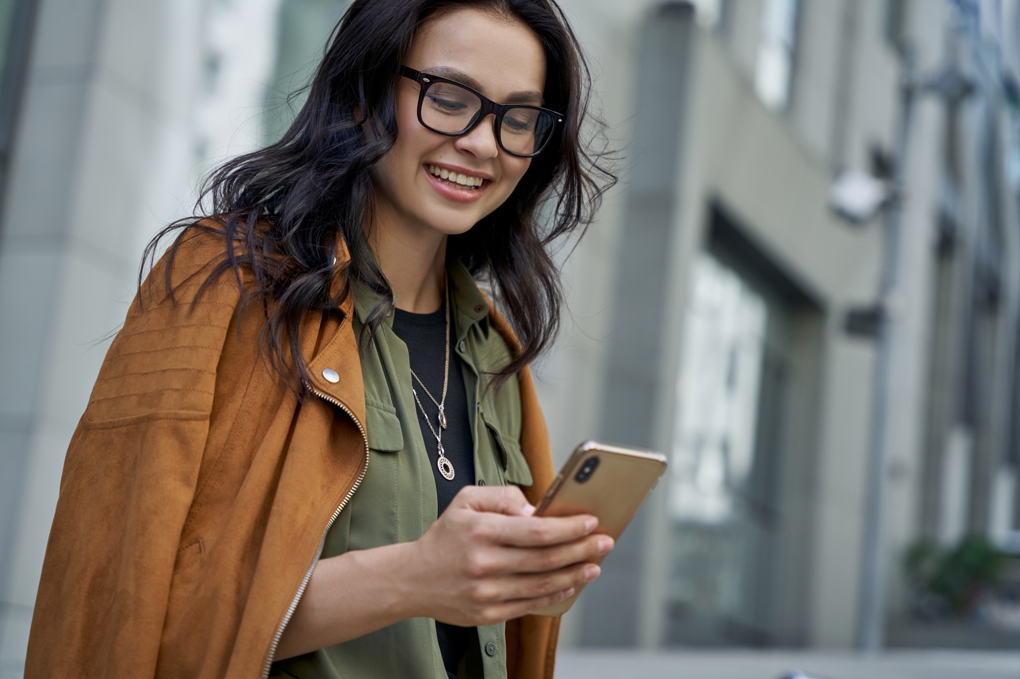 Chatting with friend. Young happy fashionable woman wearing eyeglasses walking on the city street